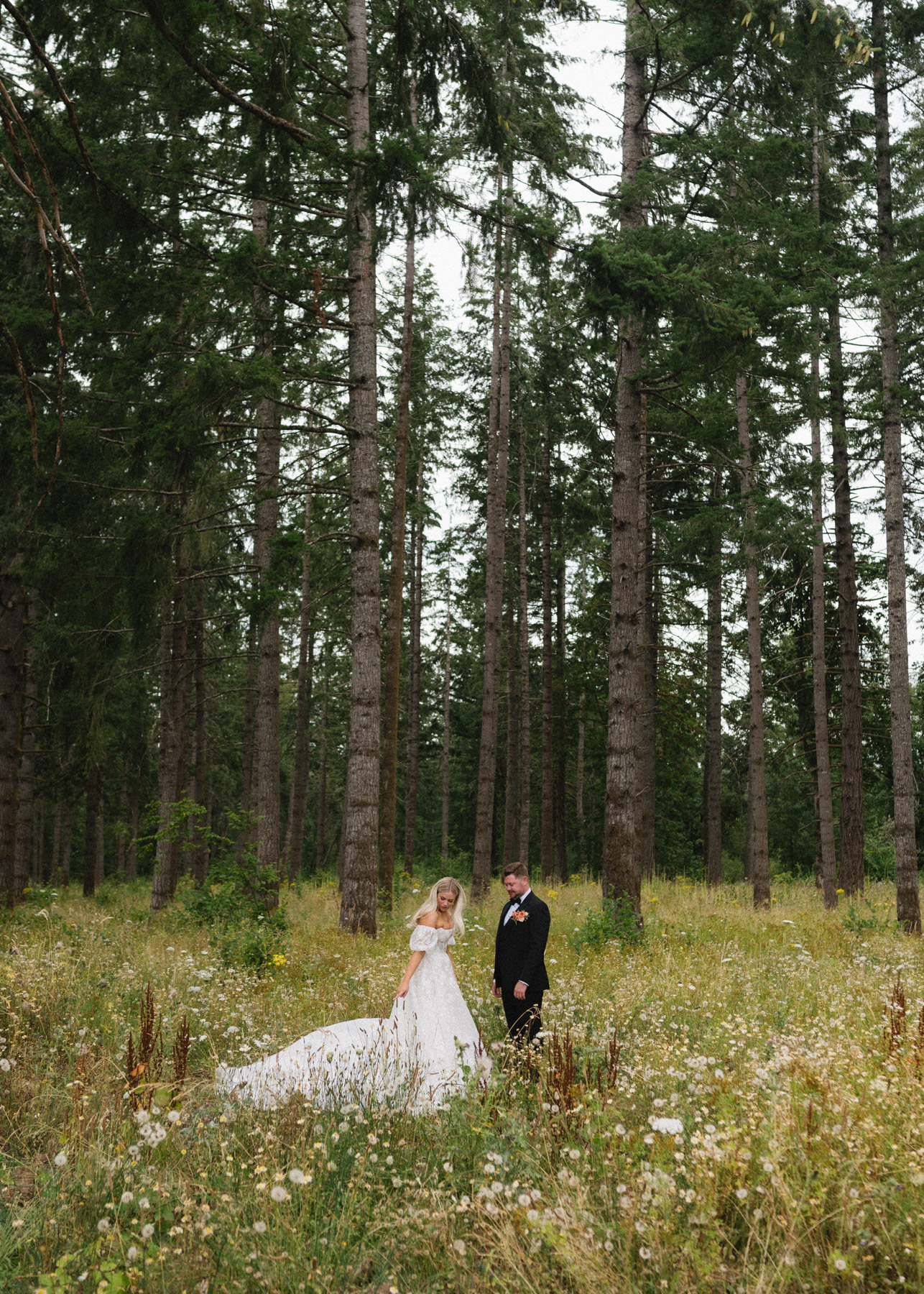 A bride and groom stand in a field