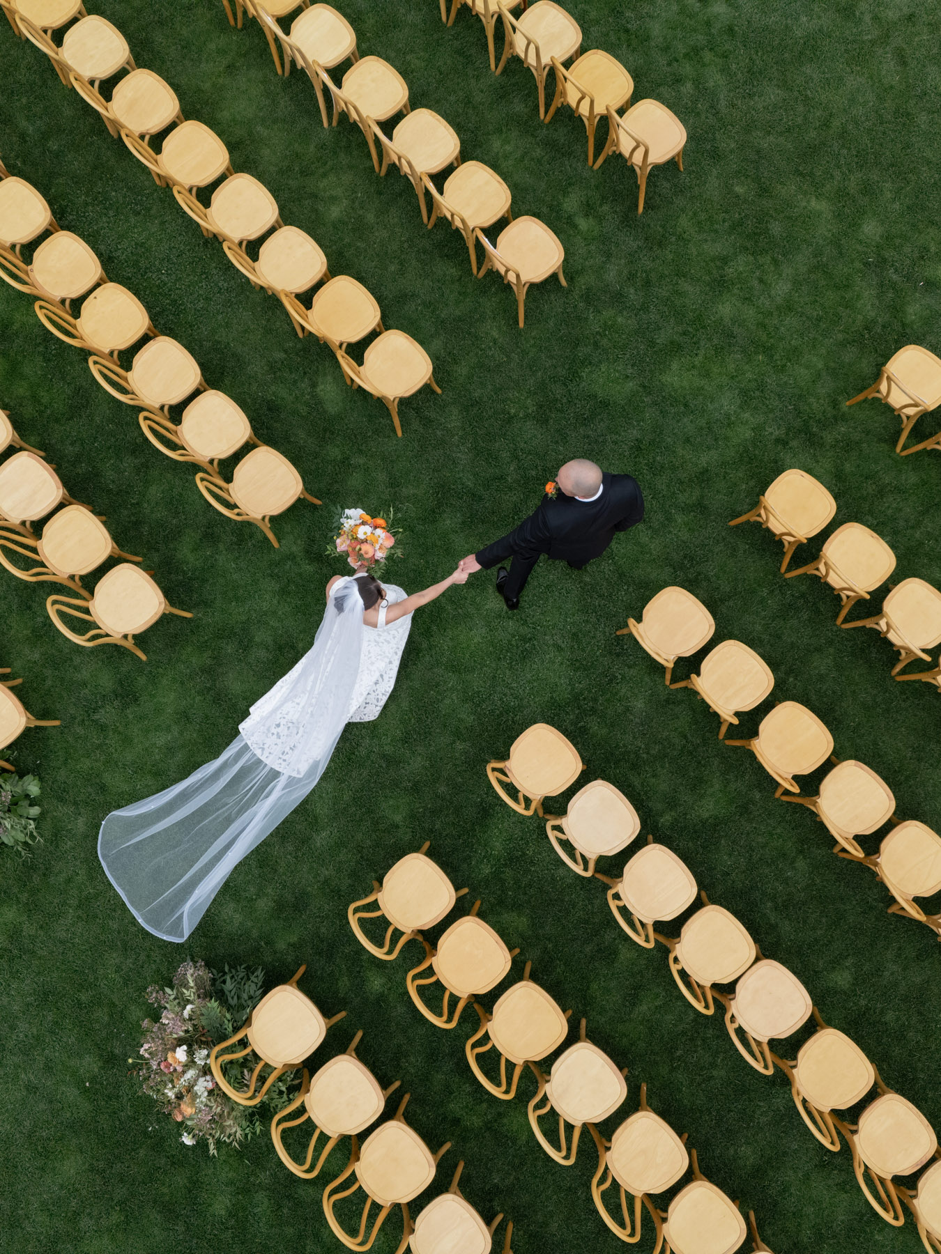 A bird's eye view of a bride and groom walking down a wedding aisle