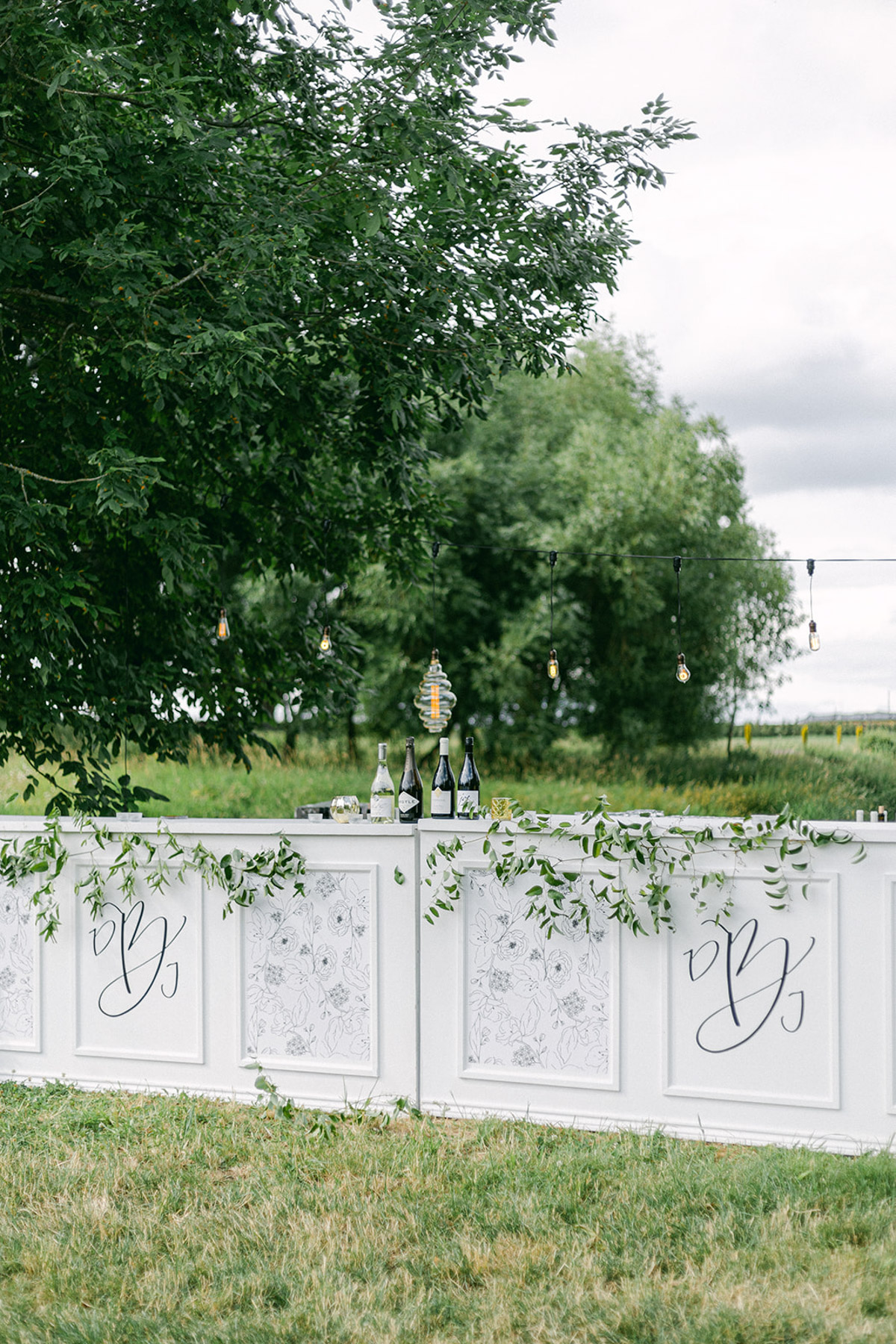 A white bar with custom wedding monogram and modern flowers by Life in Letters.